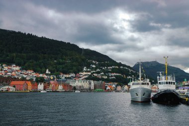 Bergen limanının ünlü manzarası ve tarihi çeyrek Bryggen. Fiyort, dağlar, gemiler, geleneksel renkli ahşap evler. Norveç, Hordaland. İskandinav simgesi.