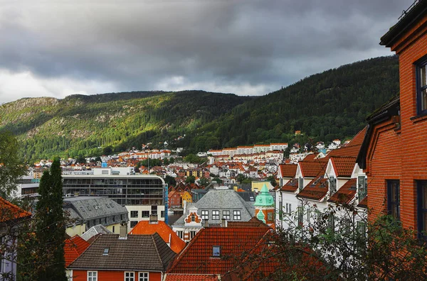 Bergen 'in resimli manzarası. Dağlar, bulutlar, güneş ışığı ve gölgeler, şehir manzarası, çatılar. Hordaland, Norveç.