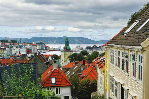 Прекрасный вид на Берген в конце лета. Домик, горы, облака, гавань, традиционные деревянные дома с черепичными крышами. Хордаланд, Норвегия
.