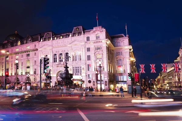 Popular tourist Picadilly circus with flags union jack in night — Stock Photo, Image