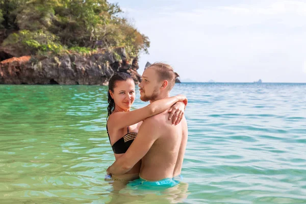 Young slim happy hipster couple on tropical beach kiss each other