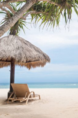 Şezlong mavi okyanusun kıyısında yakınındaki beyaz bir tropikal plajda şemsiye ile