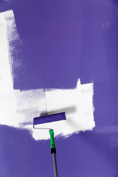 Violet paint roller on white wall — Stock Photo, Image