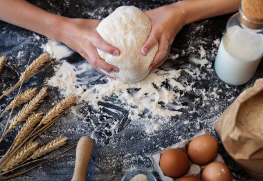 Koyu arka plan üzerinde malzemelerle hamur yoğurmak