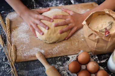 Koyu arka plan üzerinde malzemelerle hamur yoğurmak