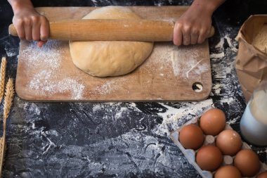 Koyu arka plan üzerinde malzemelerle hamur yoğurmak