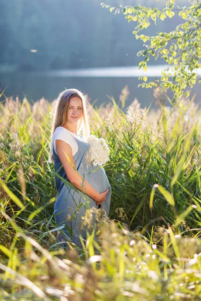 年轻怀孕妇女期待在户外花的婴儿 — 图库照片