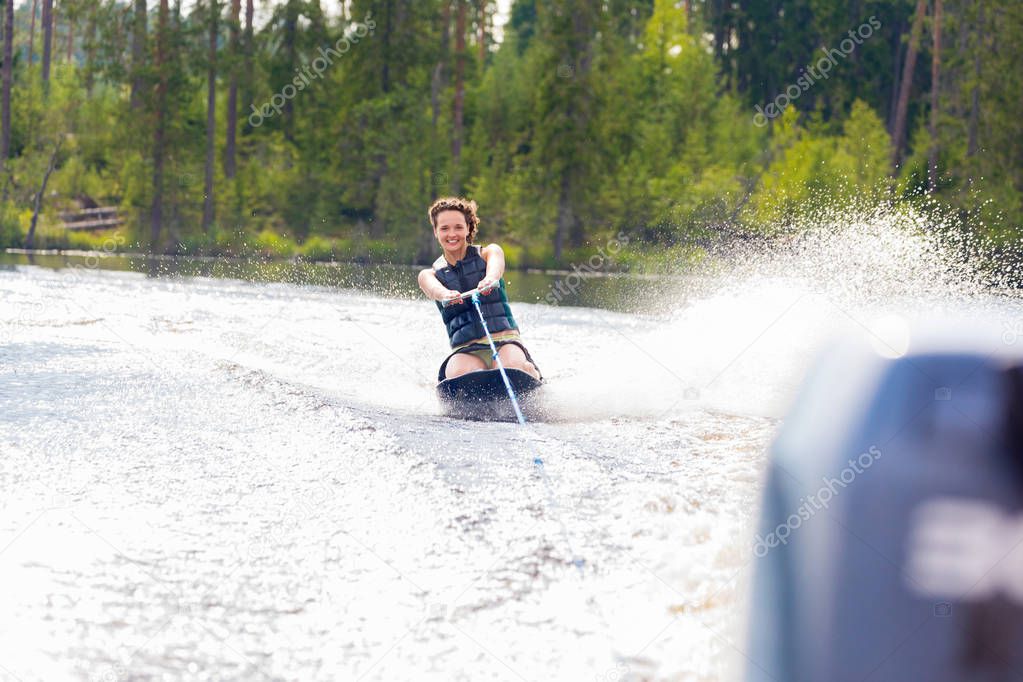 Young athletic woman riding kneeboard on a lake