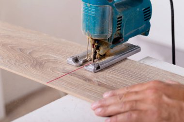 Laminat parke yükleme. Marangoz parke zemin kurulu elektrik testere ile kesme.