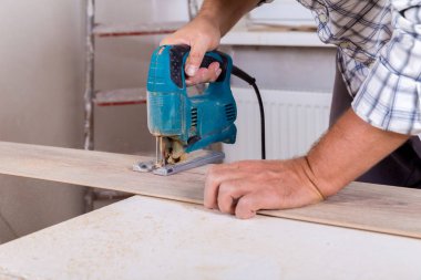 Laminat parke yükleme. Marangoz parke zemin kurulu elektrik testere ile kesme.