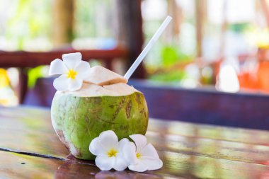 Tropikal palmiye yaprakları ve beyaz frangipani çiçekler taze Hindistan cevizi keser