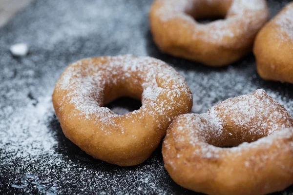 Homemade donuts with icing sugar powder on a wooden background