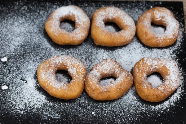 Homemade donuts with icing sugar powder on a wooden background
