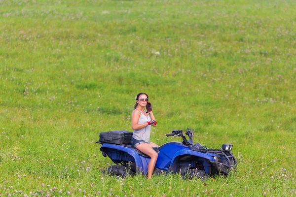 优雅的女人骑着四轮车在春天的田野 — 图库照片