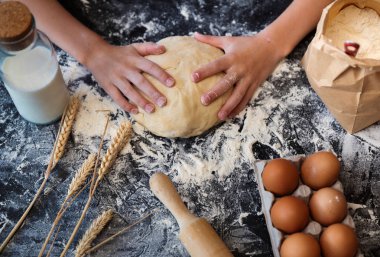 Koyu arka plan üzerinde malzemelerle hamur yoğurmak