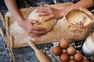 Koyu arka plan üzerinde malzemelerle hamur yoğurmak