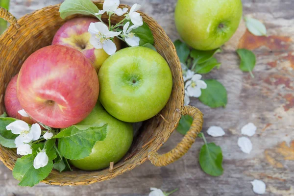 Čerstvá sladká šťavnatá červená a zelená jablka s květinami na dřevěném pozadí — Stock fotografie