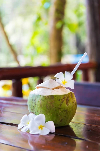 Fresh coconut cuts with tropical palm leaves and white frangipani flowers — Stock Photo, Image