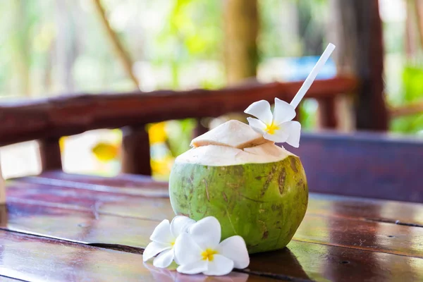 Färsk kokosnöt skär med tropisk palmblad och vita frangipani blommor Stockfoto