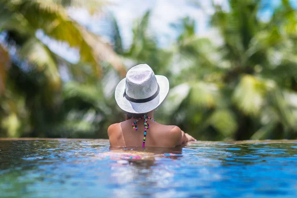 Junge schlanke brünette Frau sonnt sich im tropischen Pool — Stockfoto