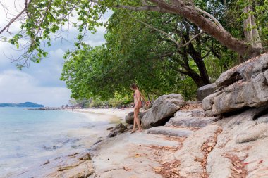 Deniz kenarındaki beyaz sahilde genç bir kadın.