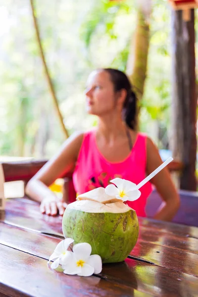 Fresh coconut drink with white frangipani flowers in front of woman tropical bar — Stock Photo, Image