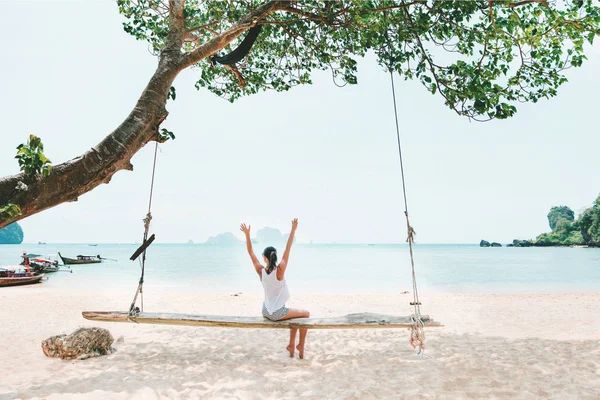 Young woman on swings on white sea beach — 스톡 사진