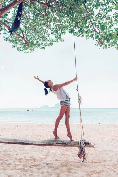 Young woman on swings on white sea beach — 스톡 사진