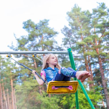 Pretty küçük sarışın kız oyun alanında açık havada sallanan