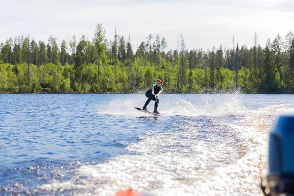 Jovem muito magro morena mulher em wetsuit equitação wakeboard onda de lancha — Fotografia de Stock