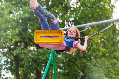 Pretty küçük sarışın kız oyun alanında açık havada sallanan