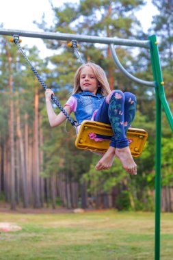 Pretty küçük sarışın kız oyun alanında açık havada sallanan