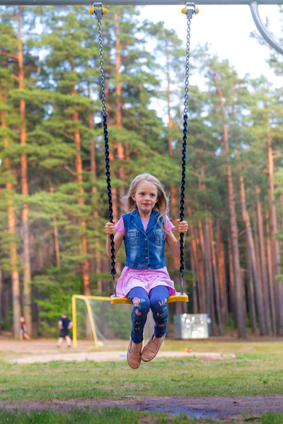 Linda menina loira balançando ao ar livre no playground — Fotografia de Stock