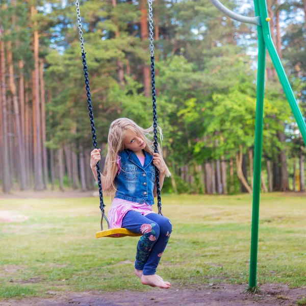 Jolie petite fille blonde se balançant à l'extérieur sur une aire de jeux — Photo