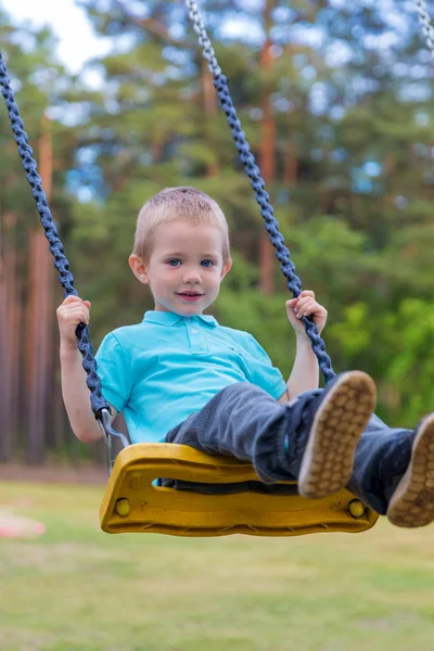 Bonito menino loiro balançando ao ar livre no playground — Fotografia de Stock