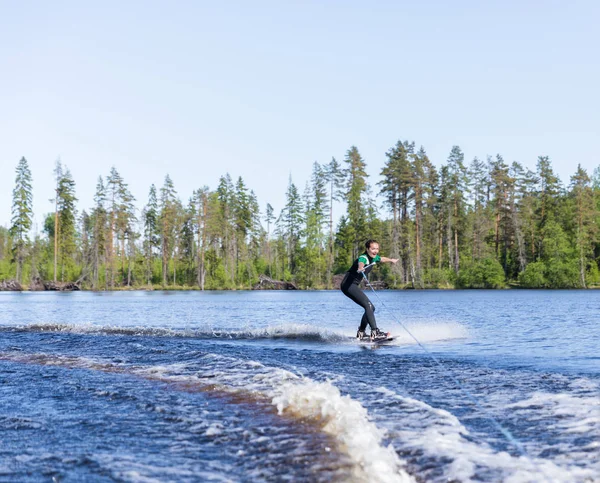 Jovem morena muito magro mulher em wetsuit equitação wakeboard na onda de lancha — Fotografia de Stock