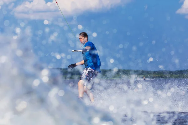 Junger aktiver Mann reitet Wakeboard auf einer Welle von einem Motorboot auf dem Sommersee — Stockfoto