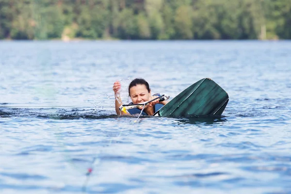 Jong pretty slim brunette vrouw paardrijden wakeboard op golf van motorboot in de zomer meer — Stockfoto