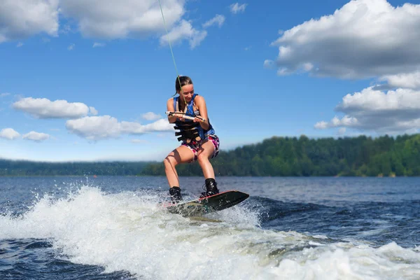 Νέα όμορφη λεπτή μελαχρινή γυναίκα ιππασία wakeboard στο κύμα του μηχανοκίνητου σκάφους στη λίμνη το καλοκαίρι Royalty Free Φωτογραφίες Αρχείου