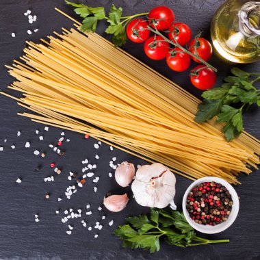 Siyah arduvaz arka plan üzerine İtalyan makarna için malzemeler.