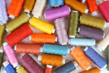 Beyaz ahşap arka planda çeşitli renklerde iplikler var. Düz yatış, üst görünüm.