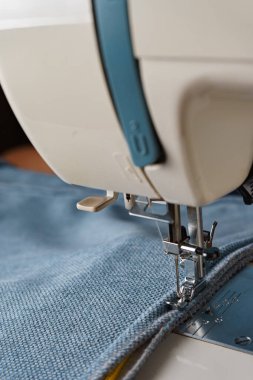Dikiş makinesi. Mavi kumaştan dekoratif bir kordon dikme işlemi.