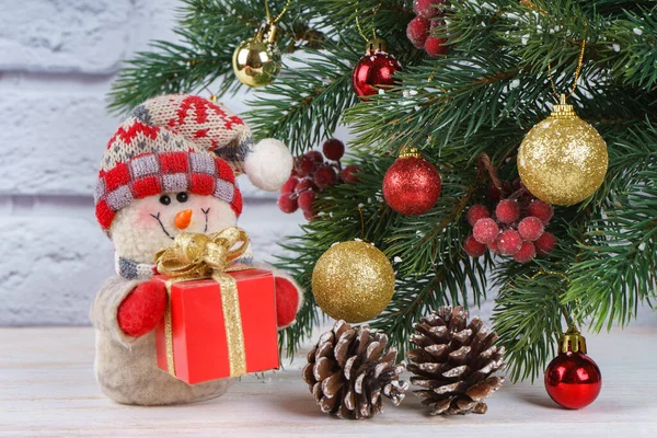 Muñeco de nieve de Año Nuevo con regalo en el fondo del árbol de Navidad — Foto de Stock