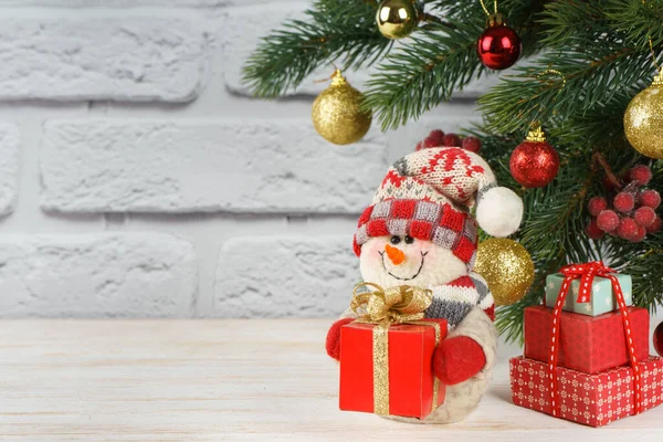 Nouvel An bonhomme de neige avec cadeau sur le fond de l'arbre de Noël — Photo