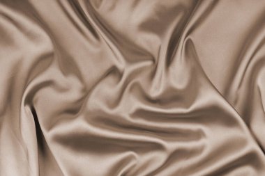 Buruşuk, buruşuk bej renkli parlak ipek kumaş. Yumuşak kıvrımlı parlak kumaş, dalga örtülü kumaş. Zarif ve zengin bir zemin, duvar kağıdı, fon. Düz yatış, üst görünüm