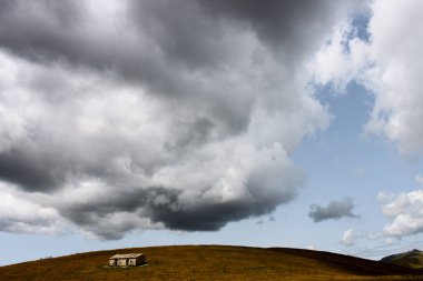 Eski terk edilmiş cowshed, büyük gri bir bulutla çatısını bastırarak