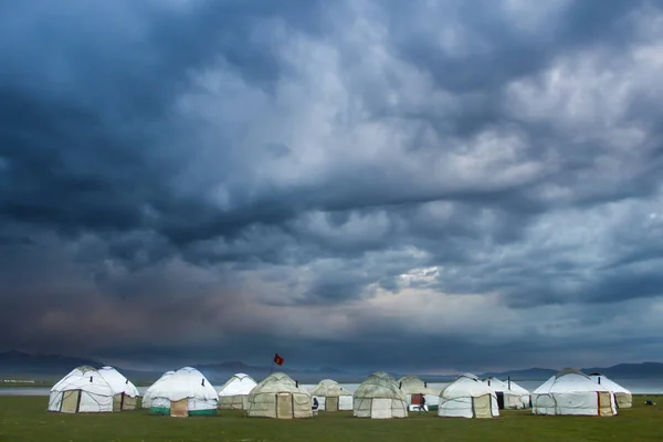 Şarkı Kol göl edilişi. Yurts karşı çok bulutlu bir gökyüzü, öğleden sonra geç saatlerde ayaktadır. Bulutlar büyük bir göz şekli gibi görünüyor. Dramatik görünüm.
