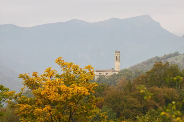 Görünümü bir manastır Kuzey Doğu ot İtalya'tipik Ekim yumuşak ışık ile sezon sonbahar. Sarı şube ön ve arka planda dağlar