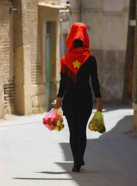 Iran, Shiraz Nisan 2014, onun elinde renkli alışveriş torbaları ile sokaklarda yürüyen genç kadın