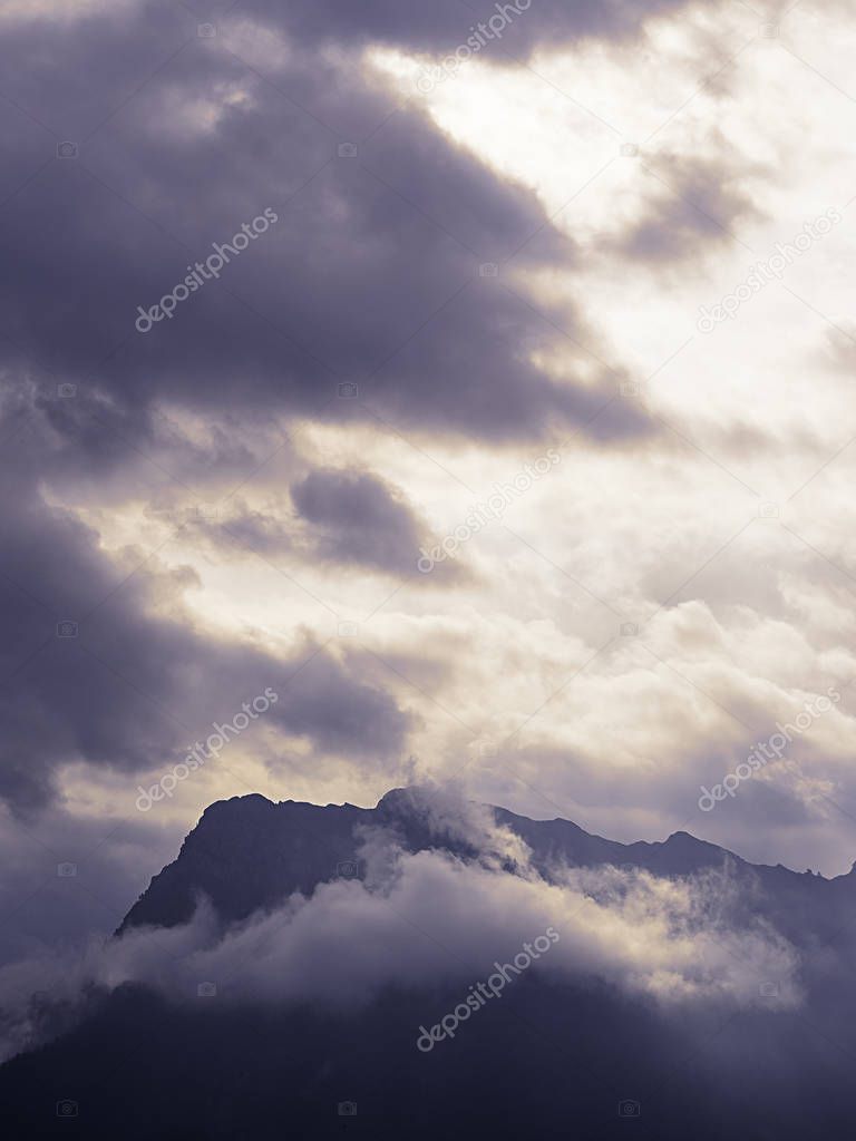 Silhouette of mountain ridge hurling itself in a cloudy sky